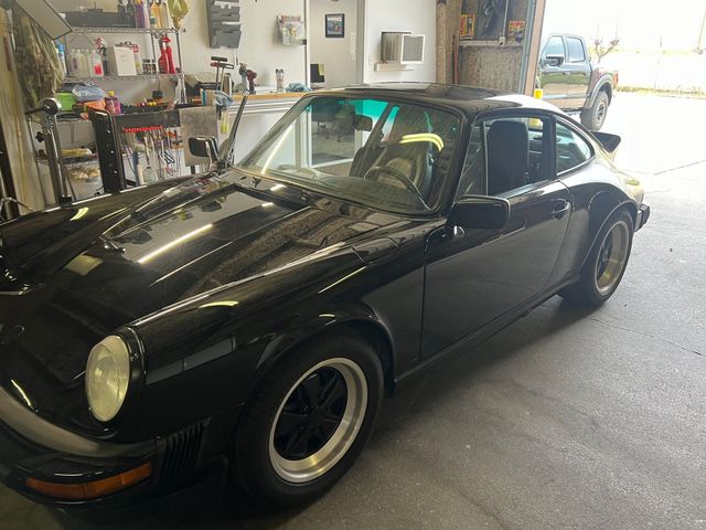 A black porsche 911 is parked in a garage