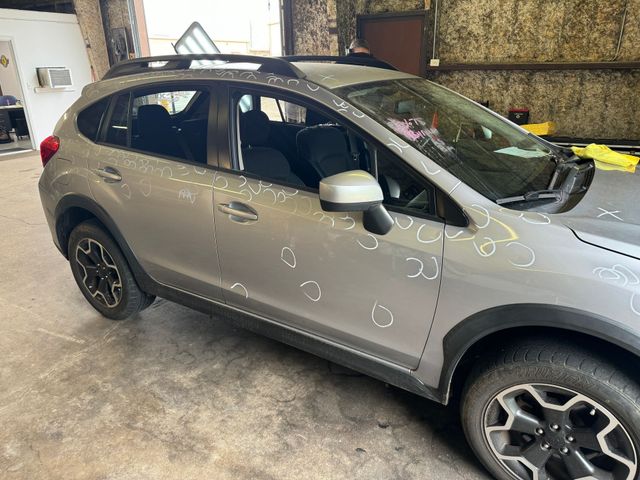 A silver subaru xv is parked in a garage.